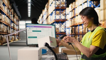 Asian male staff uses handheld scanner to register airway bill information, updating the package tracking software in real time with barcode reader and shipment details. Stock room. Camera A.