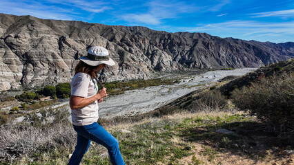 Naklejka premium The California Whitewater Canyon near Palm Spring with water flowing from the San Gabriel Mountains where frequent flooding occurs with a woman geoloigist evaluating the flood plain.