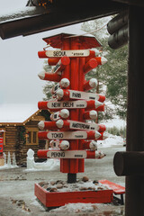 Red International Signpost with Distances to World Cities in a Snowy Winter Setting (Travel Concept)