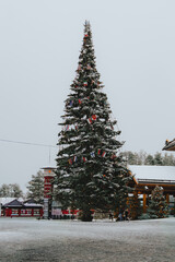 Large Outdoor Christmas Tree Decorated with International Flags in Snowy Santa Claus Village, Lapland