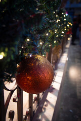 Glittery Christmas ornament hanging on festive garland with warm lights