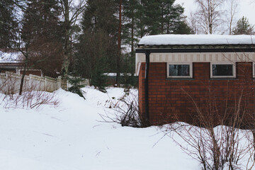 Exterior View of Red Brick Residential Building with Snow-Covered Roof and Yard in Winter