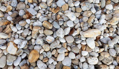 Natural background of smooth river stones in various shapes and colors. A textured surface with rounded pebbles, rocks, and organic elements. Ideal for nature, geology, environment, and texture-themed