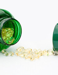 Vitamin D Capsules with Green Bottle on White Background. Vitamin D Pills Spilled from Green Container