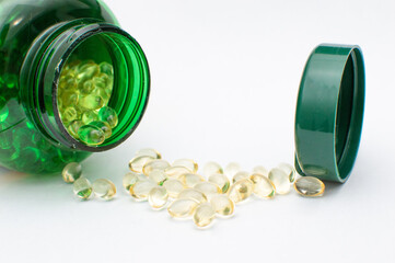 Vitamin D Capsules with Green Bottle on White Background. Vitamin D Pills Spilled from Green Container