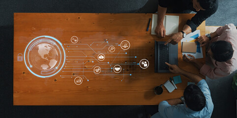 Aerial view of a modern collaborative workspace featuring a wooden table, laptop, and digital technology interface showcasing global connections and various data symbols. Trope