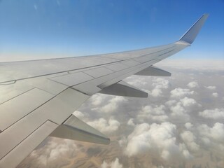 Obraz premium Aerial View of Airplane Wing Over Coastline and Sea, Red Sea, Egypt - A high-resolution aerial photograph taken from an airplane window, showing the aircraft wing above a deep blue sea with a desert c