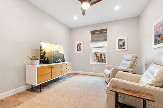 A living room with two chairs, a TV, and a ceiling fan 