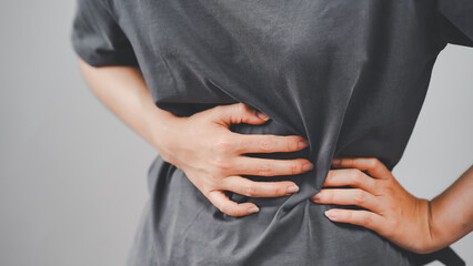 Close-up of a woman holding her side in pain, indicating stomach cramps or abdominal discomfort, ideal for health, medical, and wellness content.