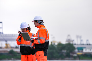 Diverse team of port engineers or logistics managers collaborating at a busy shipyard. They use a...