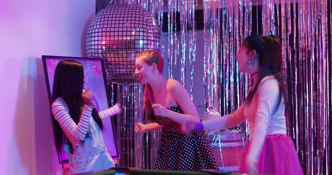 Friends celebrating birthday at pool table, phone filming and animating disco reflections on group