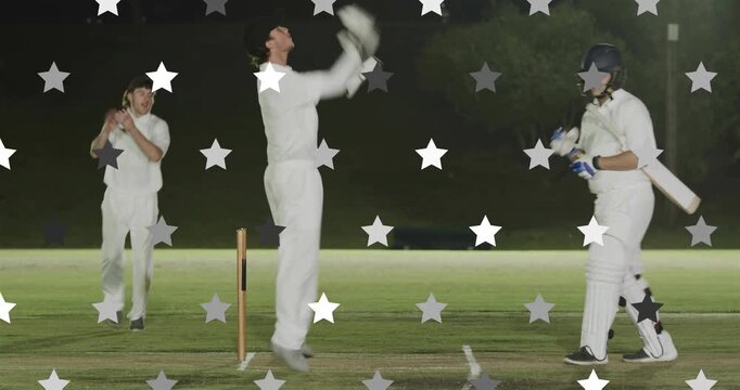 Bowler bowling floodlit pitch keeper catching as bail falling appealing out cricket batsman leaving