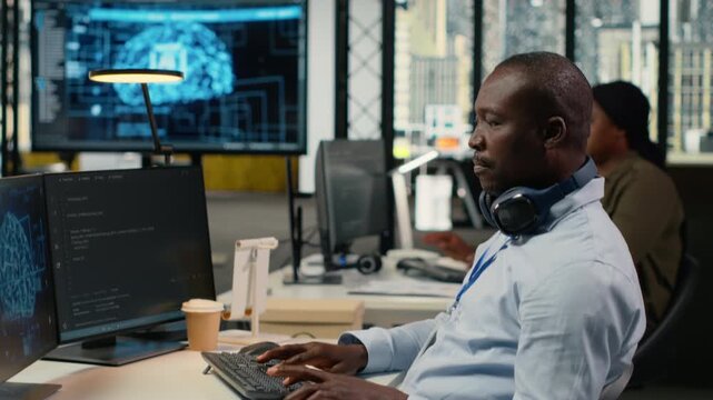 Data scientist in office doing software development to launch new features. African American man in startup company writing computer programs, doing code testing and quality assurance, camera B