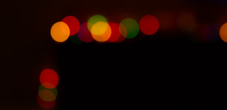 Photography of abstract colored lights on a dark black background in a narrow horizontal presentation.