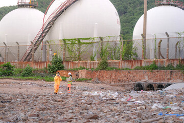Two environmental specialists in safety gear conduct a field investigation at a polluted coastal...