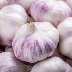Fresh garlic bulbs arranged on a clean surface, showcasing natural texture and papery layers. Bright lighting highlights the cloves, ideal for cooking, health, organic food, and ingredient themes.