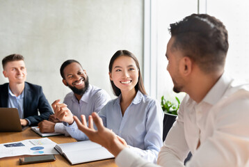In a bright office space, a diverse team of young professionals engages in a lively discussion. They are brainstorming ideas together and enjoying the collaborative atmosphere.