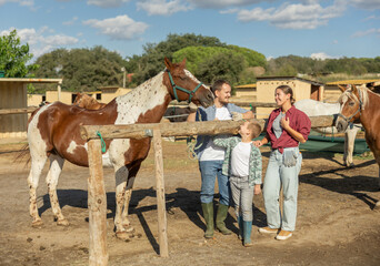Father, mother and son riding horse together at horse farm