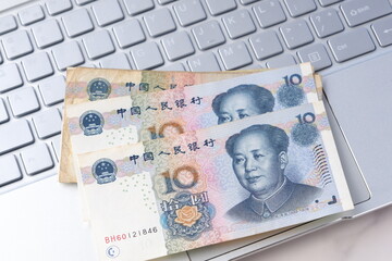 毛沢東の肖像が描かれた中国の通貨、人民元（RMB）の紙幣とノートパソコン
