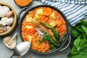 Tasty lentil soup served on grey table, flat lay