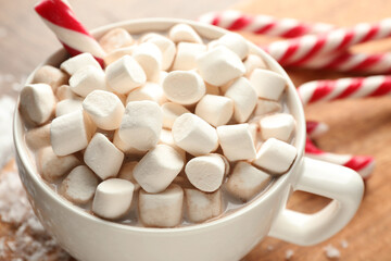 Tasty cocoa with marshmallows and candy canes on table, closeup. Christmas atmosphere