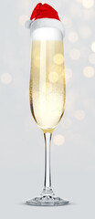 Sparkling wine in glass with small Santa hat on light grey background, bokeh lights