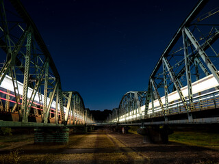 夜空に光跡を残して走る列車と鉄橋の夜景
