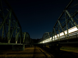 夜空に光跡を残して走る列車と鉄橋の夜景
