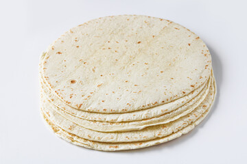 Stack of tortilla wraps placed on a clean white background, highlighting their soft texture and light, speckled surface.