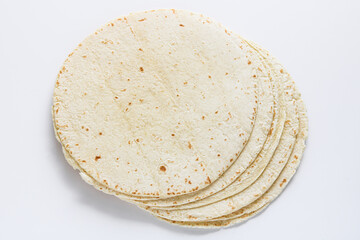 Stack of tortilla wraps arranged on a clean white background, highlighting their soft texture and light, speckled surface.