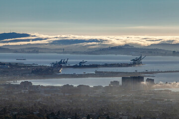 Panoramic view of Oakland cityscape and Port of Oakland industrial infrastructure in coastal fog