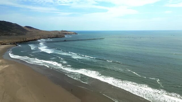 Aerial view of Puerto Eten in Chiclayo, Lambayeque, showing the fishing pier, sandy beach, and calm Pacific coastline under clear skies
