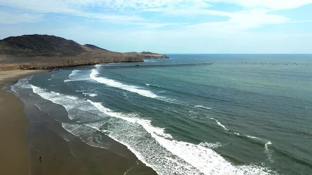 Aerial view of Puerto Eten in Chiclayo, Lambayeque, showing the fishing pier, sandy beach, and calm Pacific coastline under clear skies