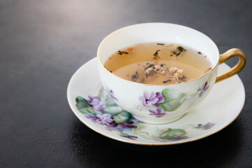 Tea in a teacup with saucer painted with purple lilac flowers