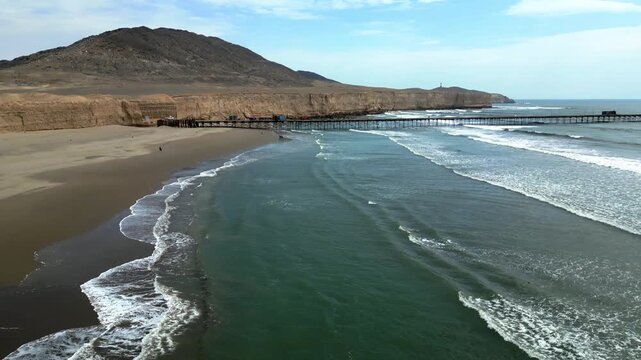 Aerial view of Puerto Eten in Chiclayo, Lambayeque, showing the fishing pier, sandy beach, and calm Pacific coastline under clear skies