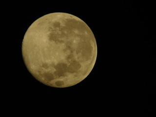 Detailed close-up view of a yellow waxing crescent moon with visible craters against a dark black sky
