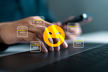 Hand using laptop with customer review icons and smiley face, showing five-star ratings from 2022 to 2026, representing satisfaction, feedback and excellent user experience in digital platforms.