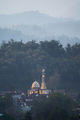 A vertical photo of a mosque located in a hilly area looks striking compared to other buildings.