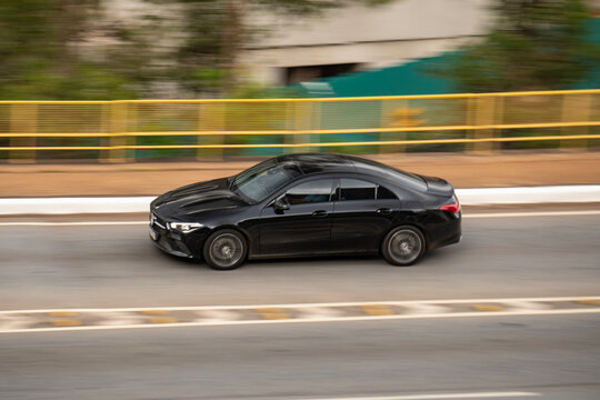 Black Mercedes Benz CLA Coupe panning shot, Luxury compact sedan speeding on road