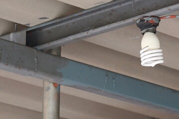 Fluorescent Light Bulb Hanging from Ceiling Structure with Rusty Metal Frame