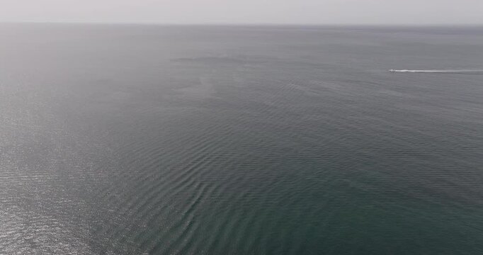 Aerial drone view of boat moving fast with Atlantic Ocean and horizon in Benagil, Algarve, Portugal, Europe