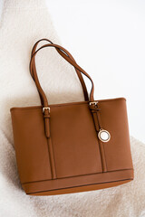 One brown woman handbag on the white interior. stylish accessories