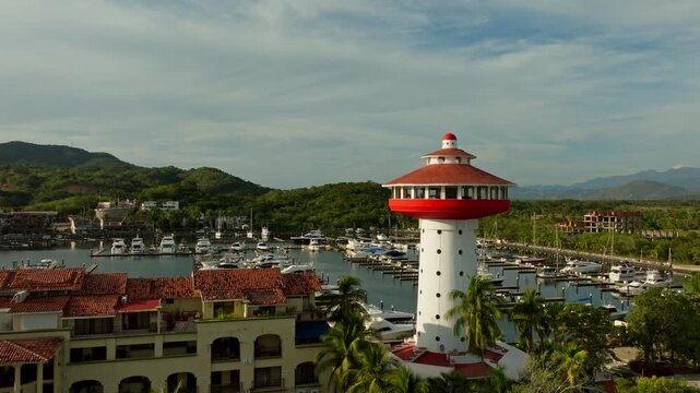 DRONE: CRANE LIKE SHOT OF THE LIGHT HOUSE AT THE MARINA IN IXTAPA, ZIHUATANEJO ( SUNSET )