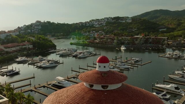DRONE: (SUNSET) SLOW ORBIT WITH THE TOP PART OF THE LIGHT HOUSE AT THE MARINA OF IXTAPA, ZIHUATANEJO
