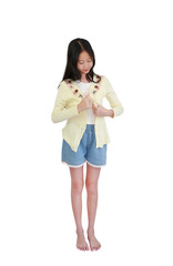 Asian girl with long, dark hair in yellow cardigan on white shirt and blue denim shorts, stands full-length on white background while adjusting sweater.
