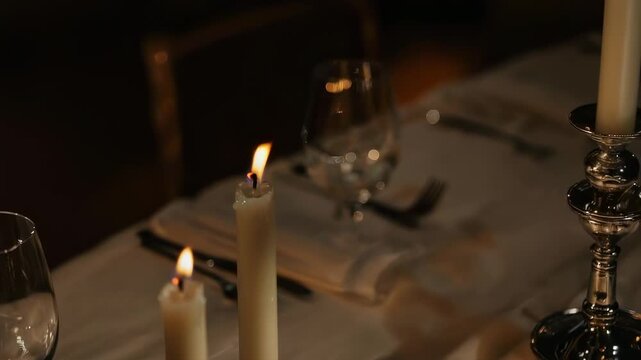 Elegant Table Setting Illuminated by Tall Cream Candles with Glassware and Silver Candlestick Warm Ambient Light