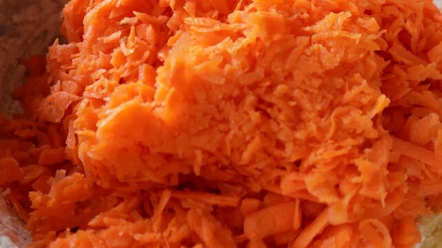 Add carrots to a mixture of flour, eggs, and sugar. Part of the preparation of a carrot cake.