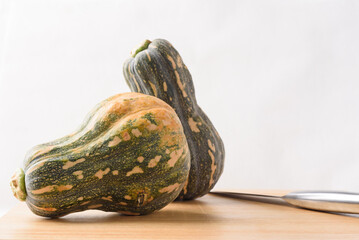 Ripe, yellow-green butternut squash after autumn harvest from an organic farm, on a white background. A healthy cooking ingredient