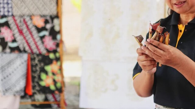 Indonesian woman holding canting tools for batik making