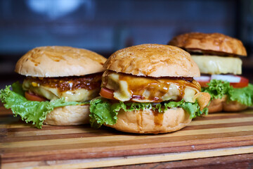 Assortment of Gourmet Cheeseburgers on Wooden Board – Fresh Homemade Fast Food Concept